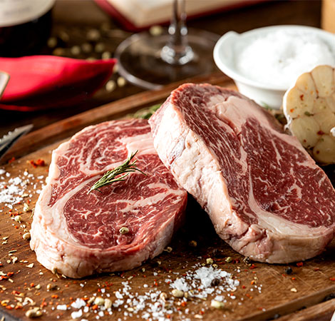 Deux entrecôtes de bœuf Halal finement persillées, assaisonnées de gros sel et romarin, prêtes pour une cuisson parfaite à la Boucherie Nador.